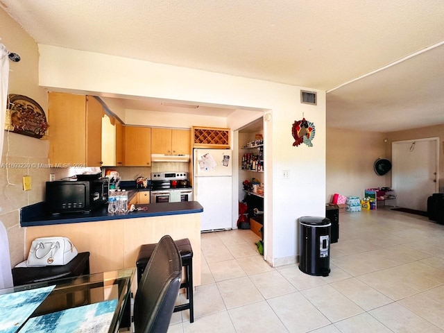 kitchen featuring kitchen peninsula, white refrigerator, light tile patterned floors, and stainless steel electric stove