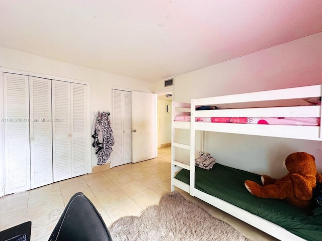 bedroom with tile patterned floors and multiple closets