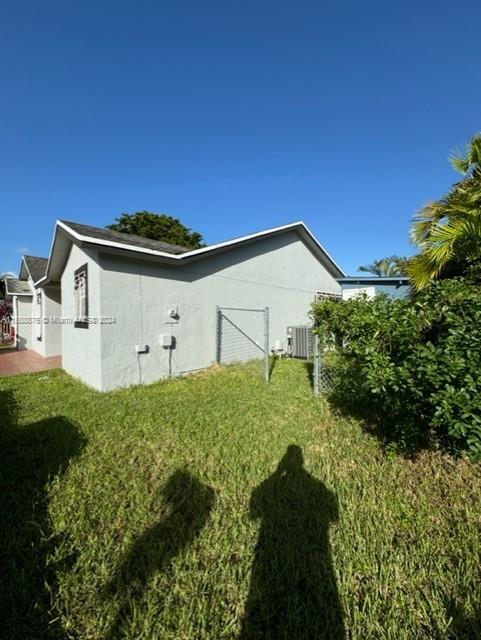 view of property exterior with central air condition unit and a lawn