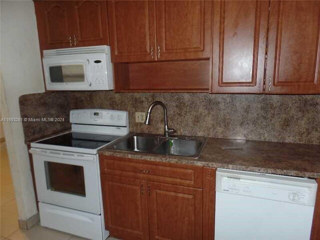 kitchen featuring backsplash, light tile patterned flooring, white appliances, and sink