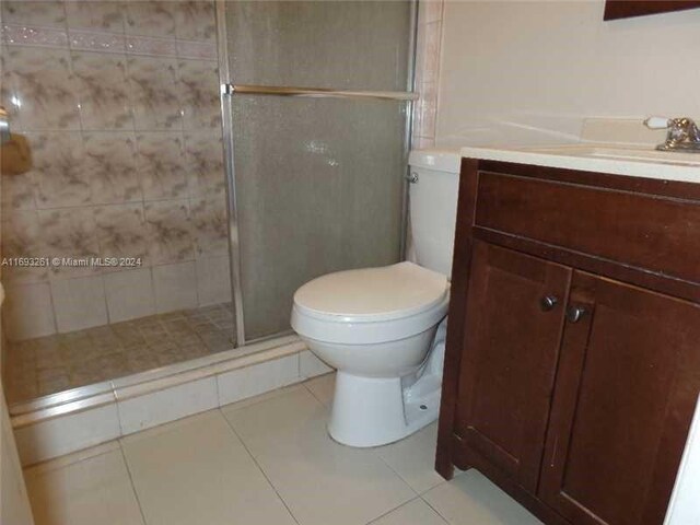 bathroom featuring tile patterned flooring, vanity, toilet, and a shower with shower door