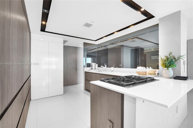 kitchen featuring a peninsula, visible vents, light countertops, modern cabinets, and stainless steel gas stovetop