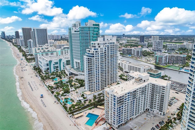 drone / aerial view with a city view, a water view, and a beach view