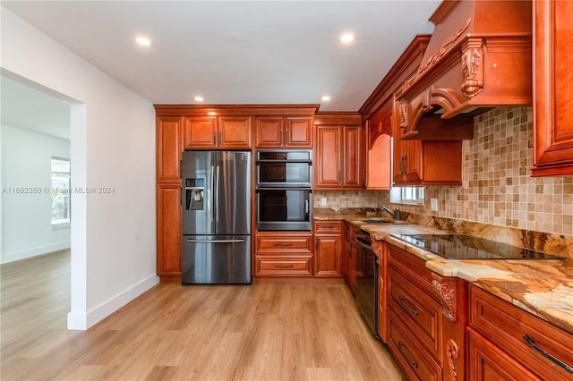 kitchen featuring sink, stainless steel appliances, light stone counters, light hardwood / wood-style flooring, and backsplash