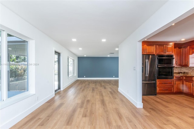 kitchen featuring decorative backsplash, light hardwood / wood-style floors, black double oven, and stainless steel refrigerator