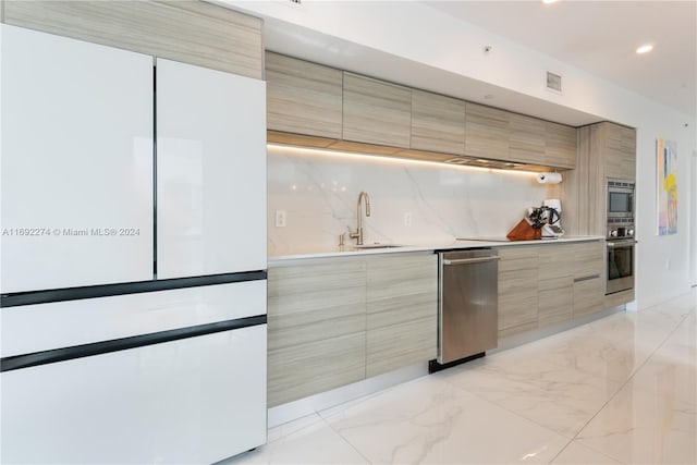 kitchen featuring light brown cabinets, stainless steel appliances, sink, and backsplash