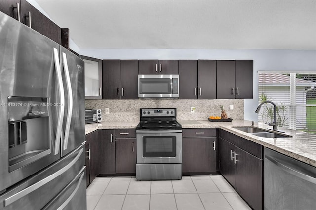 kitchen featuring appliances with stainless steel finishes, tasteful backsplash, dark brown cabinetry, sink, and light tile patterned floors