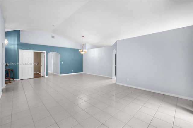 tiled spare room with an inviting chandelier and vaulted ceiling