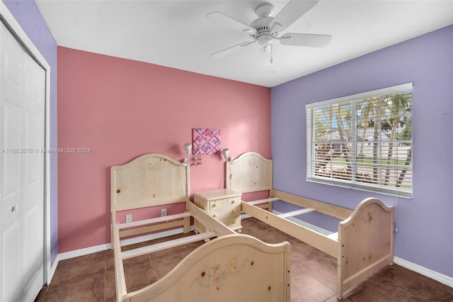 tiled bedroom with ceiling fan and a closet