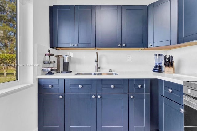 kitchen with blue cabinets, sink, and range