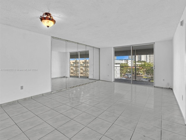 tiled spare room featuring a wall of windows and a textured ceiling