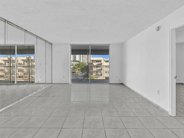 tiled empty room with a wall of windows and a textured ceiling