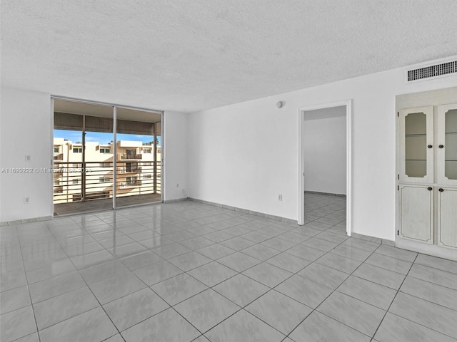 tiled spare room with a textured ceiling and floor to ceiling windows