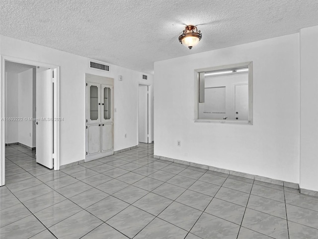 tiled spare room featuring a textured ceiling