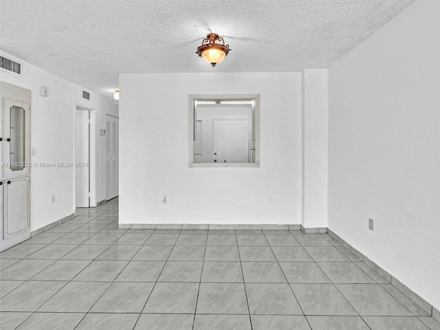 tiled spare room with a textured ceiling