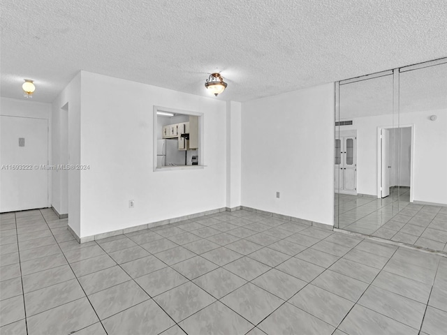 tiled empty room featuring a textured ceiling