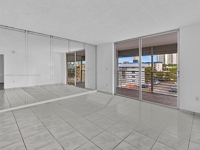 tiled spare room featuring a textured ceiling and floor to ceiling windows