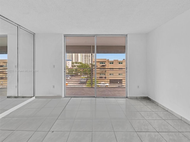 spare room featuring a textured ceiling, floor to ceiling windows, and light tile patterned floors