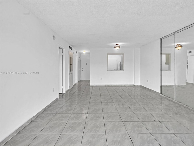 unfurnished room with a textured ceiling and light tile patterned floors