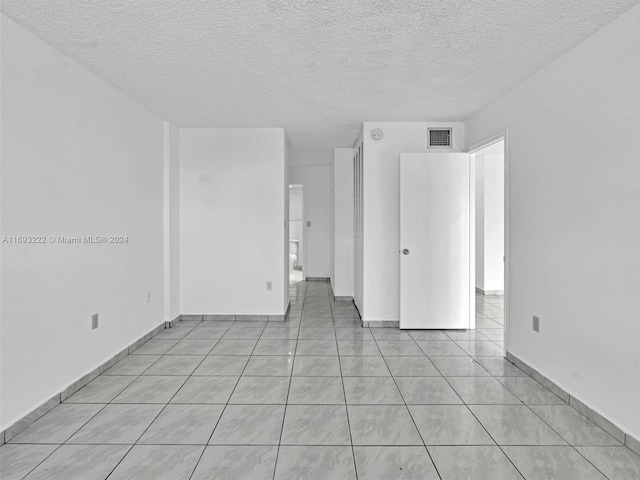 unfurnished room featuring a textured ceiling and light tile patterned floors