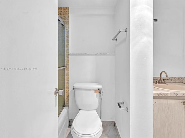 full bathroom featuring toilet, bath / shower combo with glass door, vanity, and tile patterned flooring