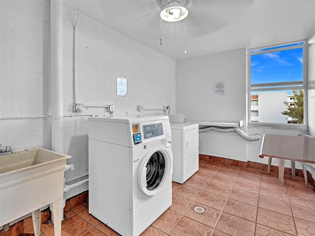 laundry area featuring washing machine and clothes dryer, light tile patterned floors, and sink