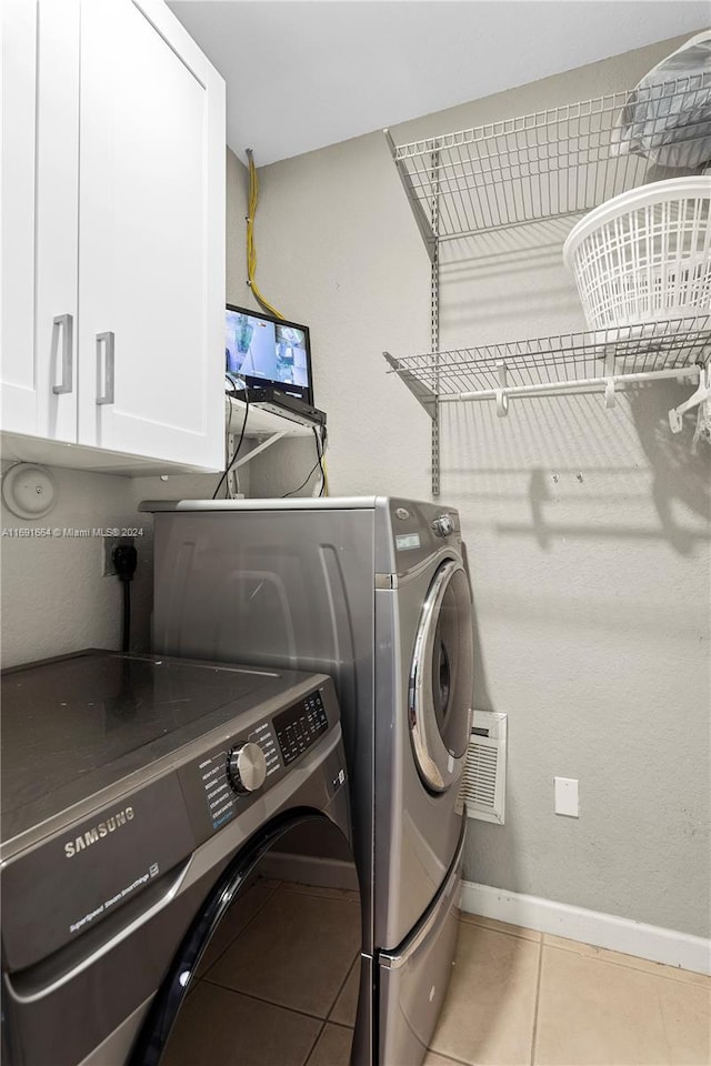 laundry area with cabinets, light tile patterned floors, and independent washer and dryer