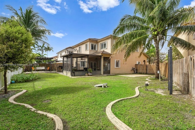 rear view of house with a lawn, a patio, and a sunroom