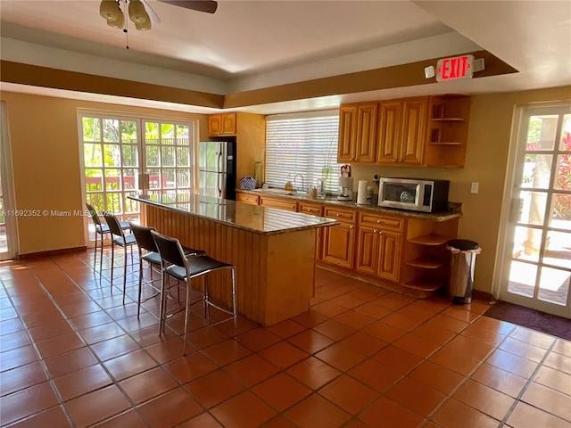 kitchen featuring a breakfast bar, appliances with stainless steel finishes, a healthy amount of sunlight, and a kitchen island