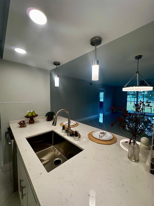 kitchen featuring hanging light fixtures, baseboards, visible vents, a sink, and light stone countertops
