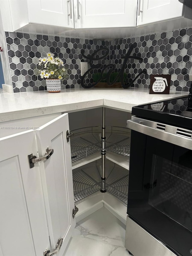 room details featuring white cabinets, light stone counters, decorative backsplash, and stainless steel range with electric cooktop