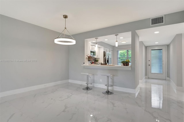 kitchen with pendant lighting, white cabinetry, stainless steel appliances, and kitchen peninsula