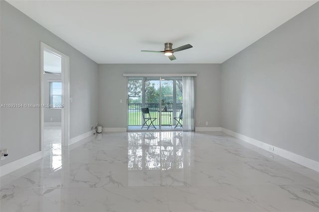 spare room with baseboards, a ceiling fan, and marble finish floor