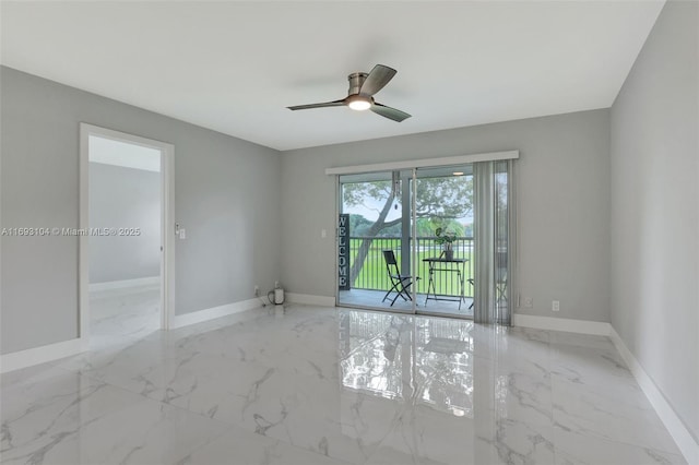 spare room featuring ceiling fan, marble finish floor, and baseboards