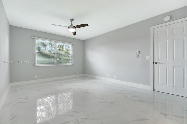 empty room featuring baseboards, ceiling fan, and marble finish floor