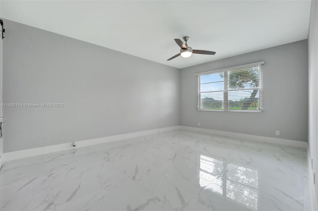 empty room with marble finish floor, baseboards, and a ceiling fan