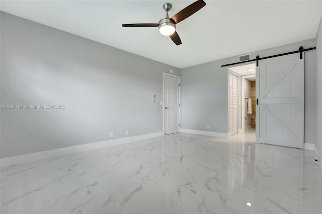 unfurnished room with a barn door and ceiling fan