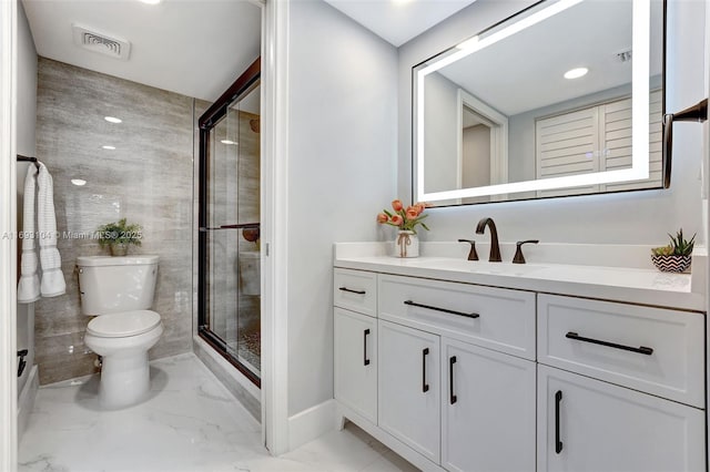 bathroom featuring vanity, a shower with door, and toilet