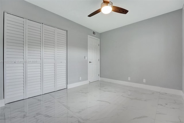 unfurnished bedroom with a closet, a ceiling fan, visible vents, marble finish floor, and baseboards