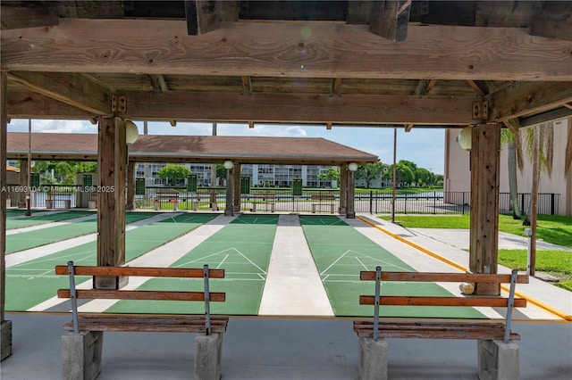 view of community featuring fence and shuffleboard