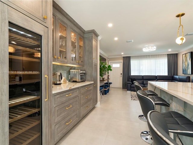 bar with tasteful backsplash, ornamental molding, light stone countertops, decorative light fixtures, and beverage cooler