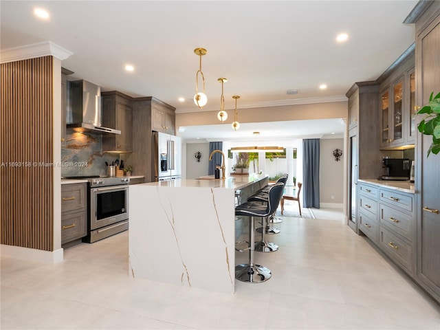 kitchen with appliances with stainless steel finishes, tasteful backsplash, wall chimney exhaust hood, hanging light fixtures, and a large island