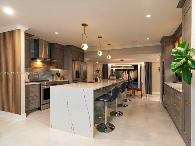 kitchen with tasteful backsplash, stainless steel appliances, wall chimney range hood, decorative light fixtures, and a kitchen bar