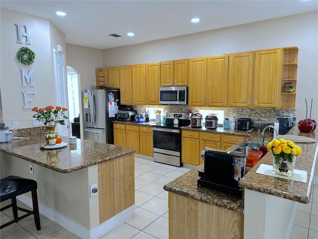 kitchen with kitchen peninsula, stainless steel appliances, and light tile patterned floors