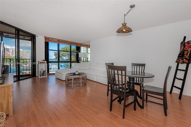 dining space featuring expansive windows, hardwood / wood-style floors, and a textured ceiling