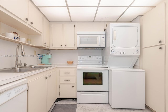 kitchen with stacked washer and clothes dryer, white appliances, sink, and a paneled ceiling