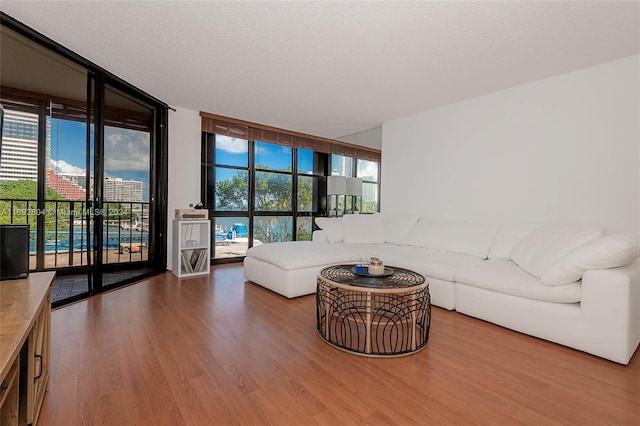 living room featuring a textured ceiling, a wall of windows, and hardwood / wood-style flooring