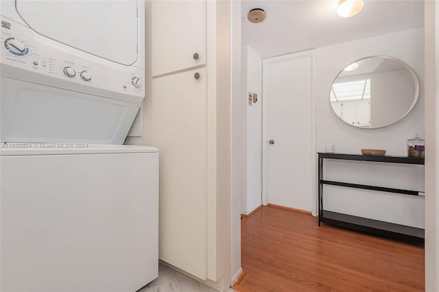 clothes washing area featuring light wood-type flooring and stacked washer and dryer