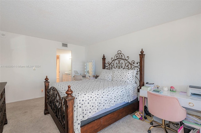 bedroom featuring ensuite bath, a textured ceiling, and light carpet