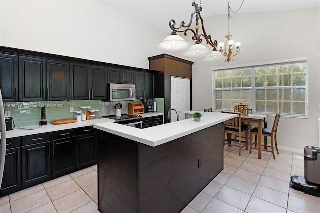 kitchen featuring an inviting chandelier, decorative backsplash, hanging light fixtures, a kitchen island with sink, and appliances with stainless steel finishes